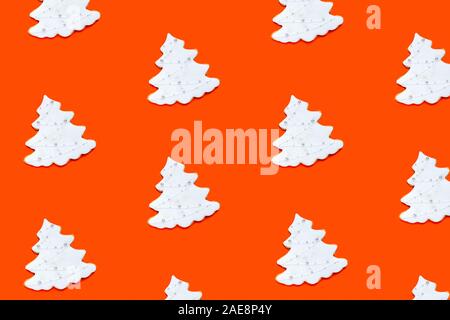 Pattern made of fir tree shaped homemade ginger cookies on orange background. Christmas concept. Stock Photo