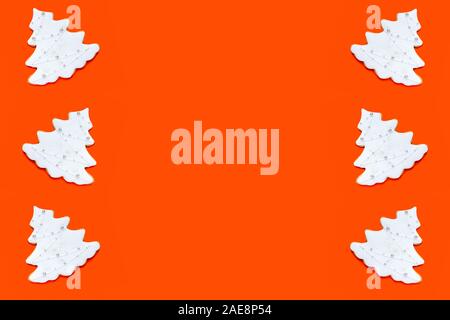 Pattern made of fir tree shaped homemade ginger cookies on orange background. Christmas concept. Stock Photo