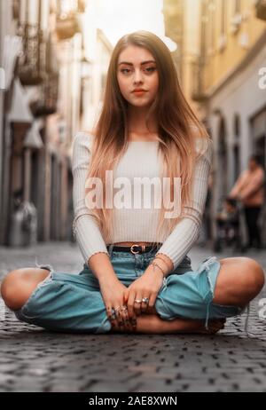 girl sitting on the ground in the street Stock Photo