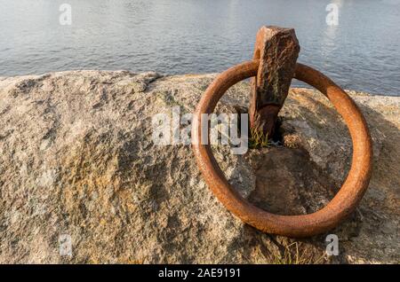 Rusty ring for the mooring of a boat on the rock by the ocean Stock Photo