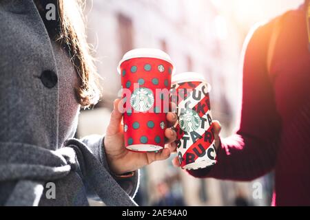 New York, USA - December 5, 2019 : Close up of a Two Young Business Woman Holding tall Christmas Starbucks Coffee on the street during sunset in New y Stock Photo