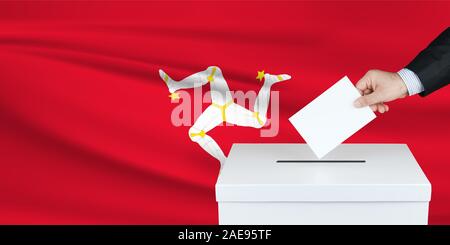 Election in Isle of the man. The hand of man putting his vote in the ballot box. Waved Isle of the man flag on background. Stock Photo