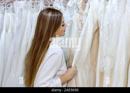 Young beautiful woman in a wedding salon chooses a wedding dress. Stock Photo