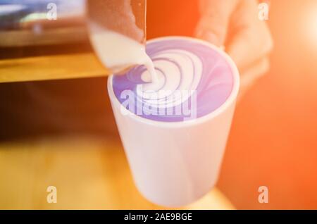 Closeup image of male hands pouring coconut milk and preparing blue matcha latte. Blue latte art Stock Photo