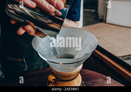 Close up of pour-over coffee in the dripper. Barista preparing filter coffee outdoor. Alternative coffee brewing Stock Photo