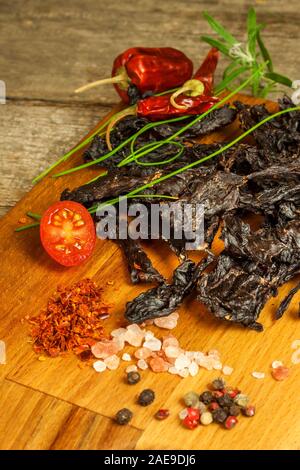 Dried meat on kitchen table. Domestic production of dried beef. Meat marinated in chilli. Diet food. Durable food. Proteins for athletes. Stock Photo