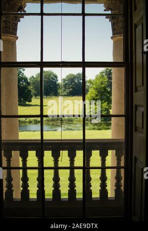 Sash window in the long gallery overlooking formal gardens & lake, showing architectural details of the building (stone columns & balustrade) Stock Photo