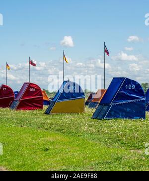 Row of colourful strandkorbs hooded beach chairs beside Elbe River Ottendorf Lido Cuxhaven Lower Saxony Germany. Stock Photo