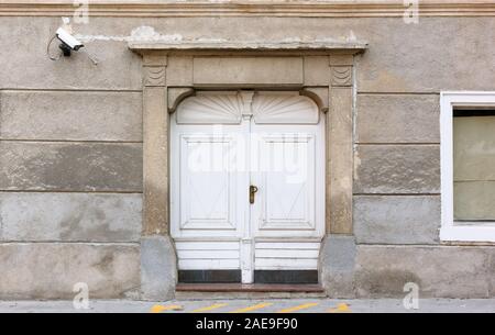 Entrance of a historic building, with a modern surveillance camera on the wall and a yellow no parking sign on ground Stock Photo