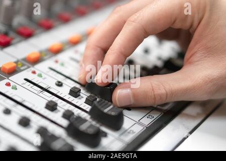 Male hand on control Fader on console. Sound recording studio mixing desk with engineer or music producer . Stock Photo