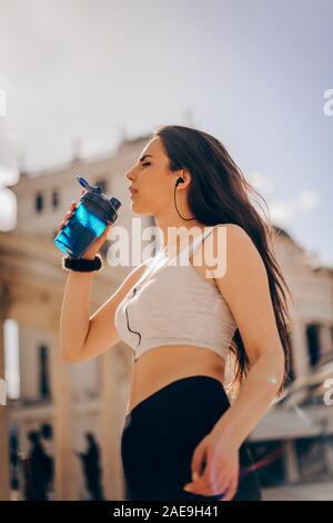 Thirsty woman drinking water to recuperate after rollerblading Stock Photo