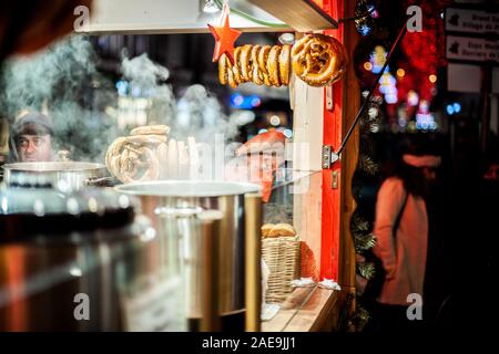 Strasbourg, France - Dec 20, 2016: Multiple sweets alsatian bretzels and mulled wine stainless steel cauldron with steam during iconic annual Marche de noel in Alsace Stock Photo