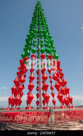 Melbourne, Australia - November 16, 2009: Green and red plastic artificial Christmas tree sculpture against blue sky. Stock Photo