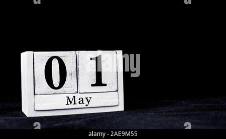 May 1st, First of May, Day 1 of month May - vintage wooden white calendar blocks on black background with empty space for text Stock Photo