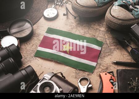 Suriname Flag Between Traveler's Accessories on Old Vintage Map. Tourist Destination Concept. Stock Photo