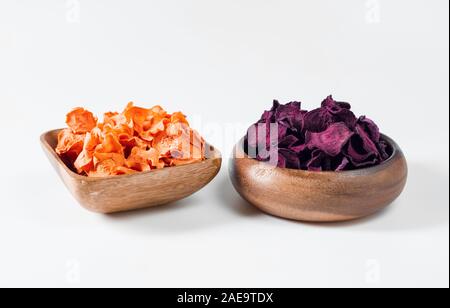 Dried carrot and beet chips in a wooden bowl on a white background. Vegetarian diet food. Horizontal orientation. Close up. Stock Photo