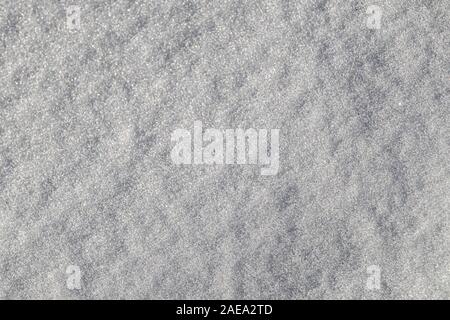 A close-up view of a surface covered in snow shows the grainy texture of the fallen snowflakes in aggregate. Stock Photo