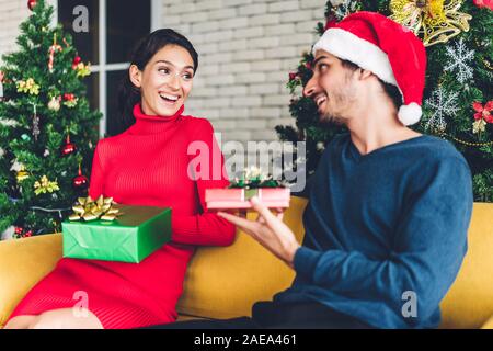 Romantic sweet couple in santa hats having fun decorating christmas tree and smiling while celebrating new year eve and enjoying spending time togethe Stock Photo