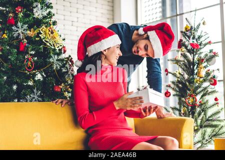 Romantic sweet couple in santa hats having fun decorating christmas tree and smiling while celebrating new year eve and enjoying spending time togethe Stock Photo