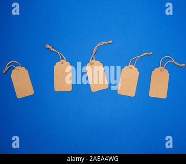 set of empty paper brown rectangular tags on a rope, price tags are on a blue trend background, top view Stock Photo