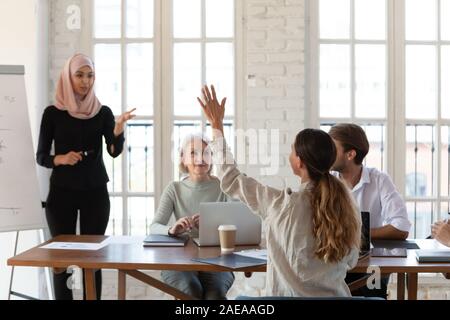 Young businesswoman rising hand to ask question to arabian speaker. Stock Photo