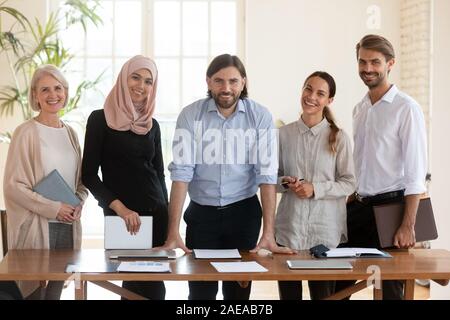 Portrait of confident male team leader with smiling diverse colleagues. Stock Photo