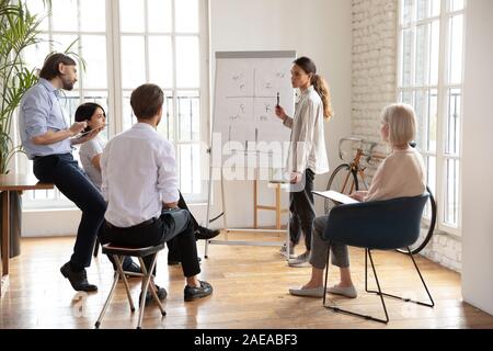 Concentrated multiracial middle aged and young colleagues listening to presenter. Stock Photo