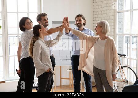 Happy international team giving high five to each other. Stock Photo