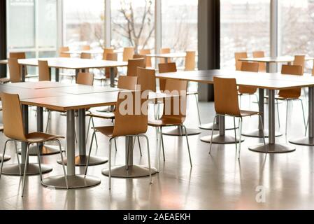 Interior of an empty canteen with modern tables and chairs lit by daylight through large view windows Stock Photo