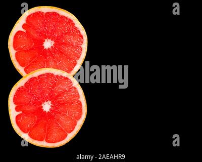 Two grapefruit slices isolated on black background. Copy space. Stock Photo