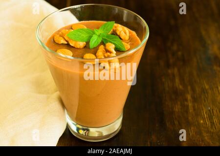 Dessert chocolate pudding with nuts in a glass on a wooden table. Close-up Stock Photo