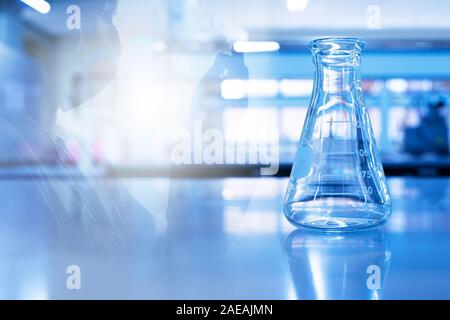 single science glass flask with double exposure scientist holding tube in chemistry blue laboratory background Stock Photo