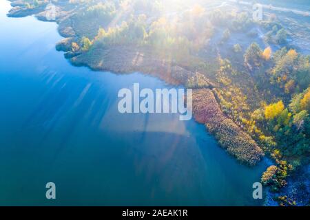 Aerial view of a beautiful island with colorful trees in autumn. Nature landscape on a sunny day with magical sunlight Stock Photo
