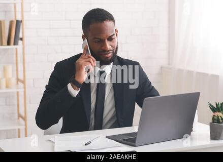 Serious entrepreneur having phone conversation, using laptop Stock Photo