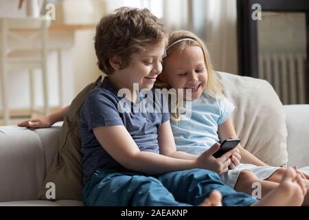 Little kids using smartphone spend free time on-line at home Stock Photo