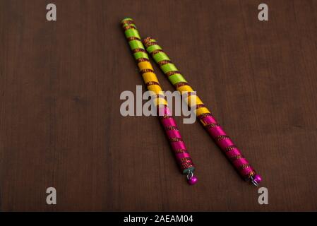 Dandiya sticks on a brown background. Raas Garba or Dandiya Raas is the traditional folk dance form the state of Gujarat & Rajasthan in India. Stock Photo