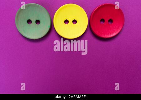 Three large multi-colored buttons on a pink background. Copy space. Stock Photo
