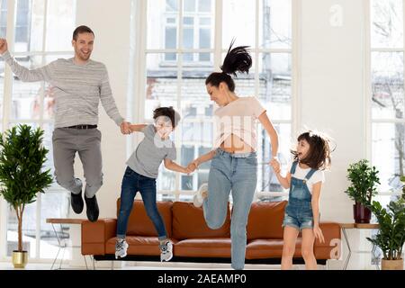 Happy family with two children jumping at home. Stock Photo