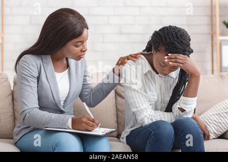 Female psychologist consoling depressed woman at personal consultation in office Stock Photo