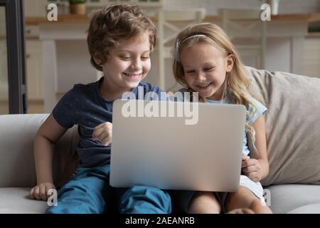 Two little kids using laptop play online game at home Stock Photo