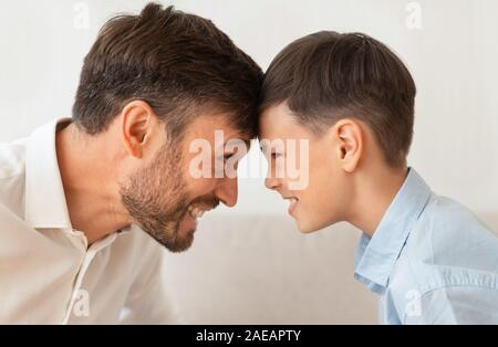 Happy Father And Son Bowing Heads Touching Foreheads, White Background Stock Photo