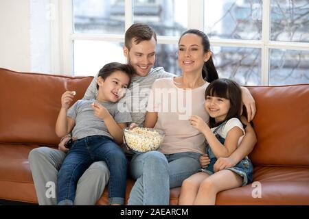 Happy young family and preschool children watching funny tv show Stock Photo