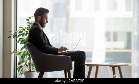 Serious Arabic businessman busy using laptop in office Stock Photo