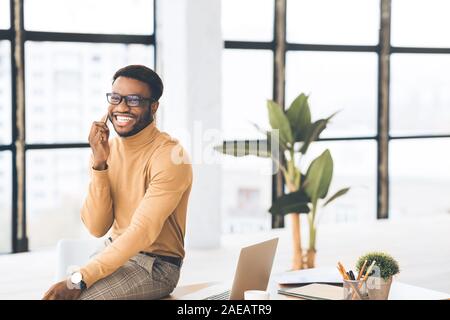 Black guy talking on phone sitting on the table Stock Photo