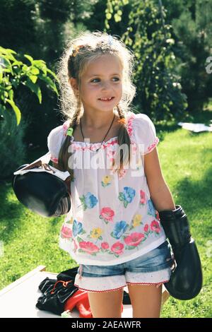 Purity, happiness. Portrait of little caucasian girl wearing boxing gloves for sport game. Cute female model looks happy, laughting. Childhood, art, s Stock Photo