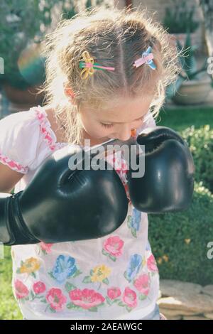 Preparation. Portrait of little caucasian girl wearing boxing gloves for sport game. Cute female model plays, looks happy, laughting. Childhood, art, Stock Photo