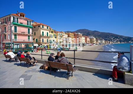 People on benches at the bathing beach of Alassio, Riviera di Ponente, Liguria, Italy Stock Photo