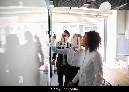 Motivated diverse employees brainstorm develop strategies on whiteboard Stock Photo