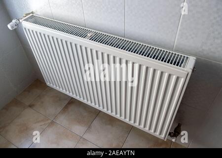 White metal heating radiator mounted on a wall in room interior. Stock Photo