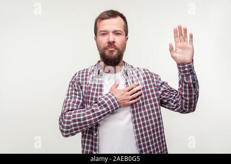 I swear! Portrait of responsible bearded man in plaid shirt keeping hand on chest making promise, swearing to tell the truth, be honest dedicated. ind Stock Photo